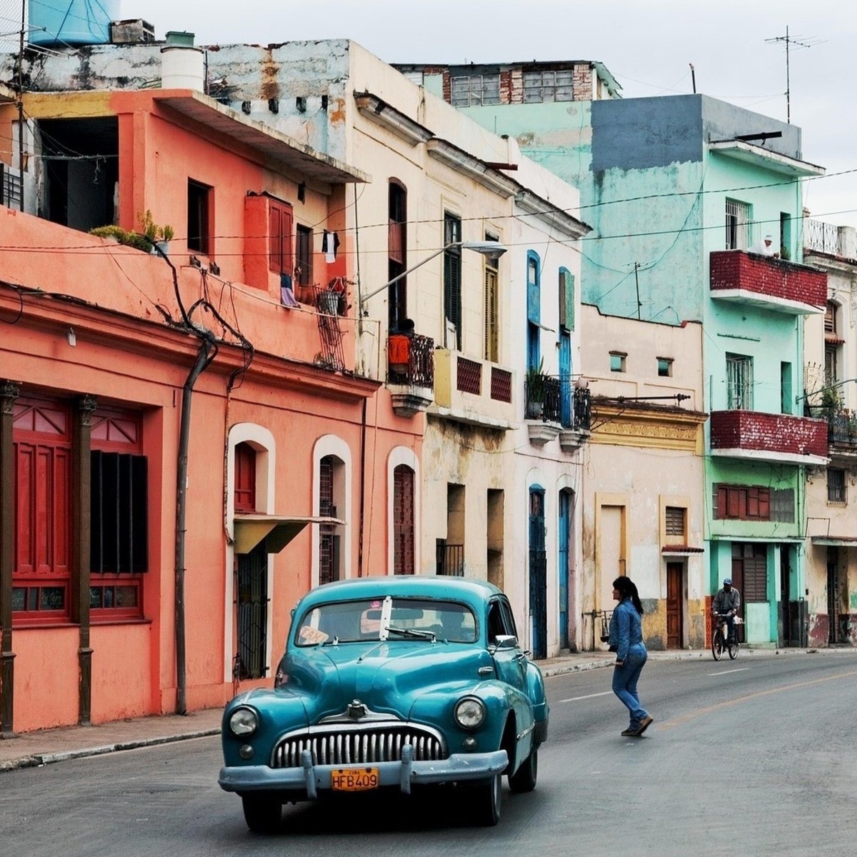 Completely Cuba - blue classic car in road in front of multicoloured buildings