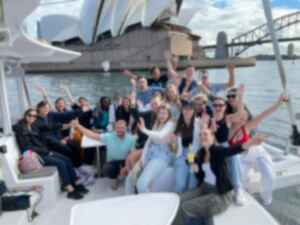 Group on Sydney Harbour cruise with hands up in front of Sydney Opera House