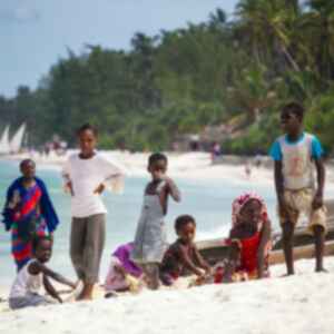 kids on a white sand beach in zanzibar with palm trees in the background