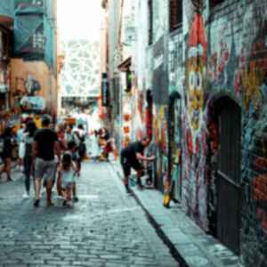 People walking down a busy lane plastered with street art in Melbourne