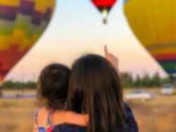 Au pair and child watching hot air balloons