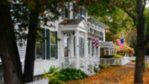 An American home with flags hanging ourside and autumn leaves on the ground