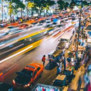 Timelapse photo of a busy Bangkok street lined with Tuk Tuks and market stalls