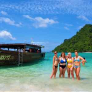 Travellers posing next to traditional thai boat on beach