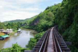 Train tracks running along the side of a densely forested mountain and the River Kwai