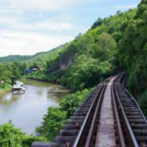 Train tracks running along the side of a densely forested mountain and the River Kwai