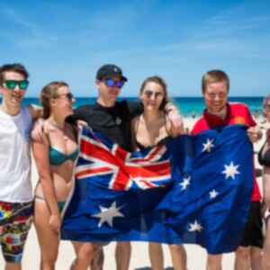 Travellers on a beach holding an Australian flag