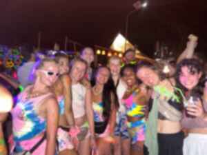 A group of travellers in colourful clothes and face paint drinking and dancing