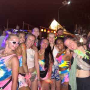 A group of travellers in colourful clothes and face paint drinking and dancing