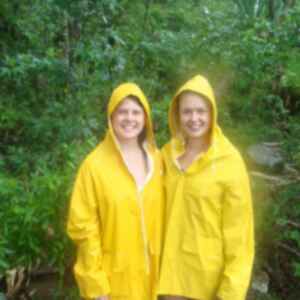 Travellers in raincoats standing in front of dense vegetation