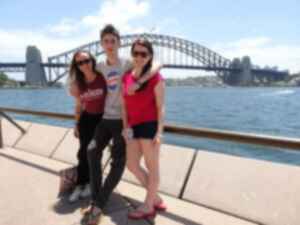 Three travellers standing in front of the Sydney Harbour Bridge and surrounding harbour