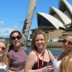 A group of travellers on a boat in front of the Sydney Opera House