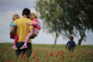 A man walking with children through a field of poppies