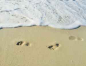 Footsteps in the sand in front of the sea