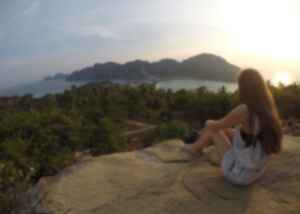 A travellers sits on a rock overlooking Koh Phi Phi island and surroundings