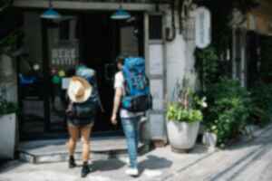 Two travellers with backpacks entering a hostel 